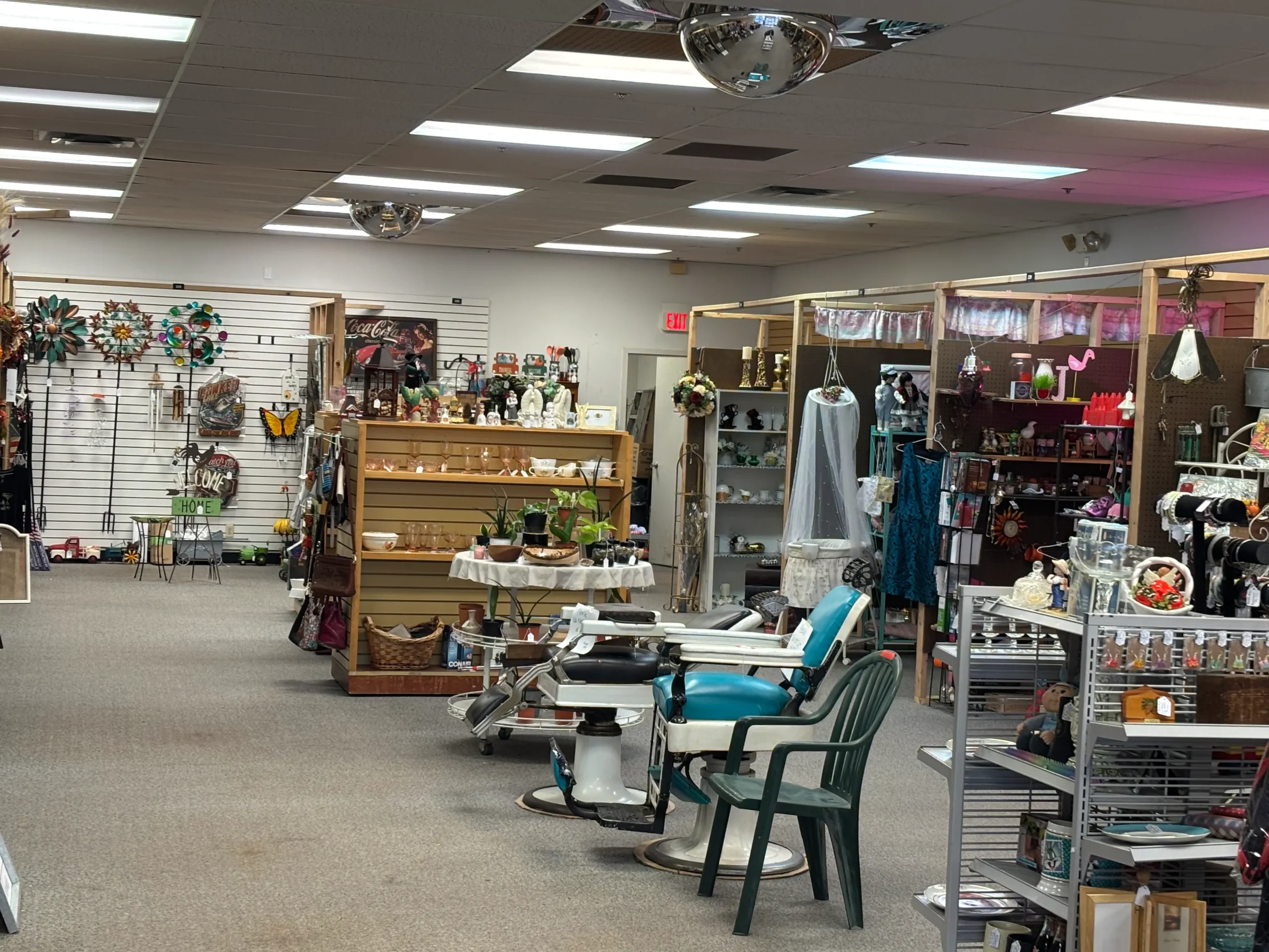 A vintage-style shop interior showcasing various decorative items, plants, and display shelves, with chairs positioned for customers