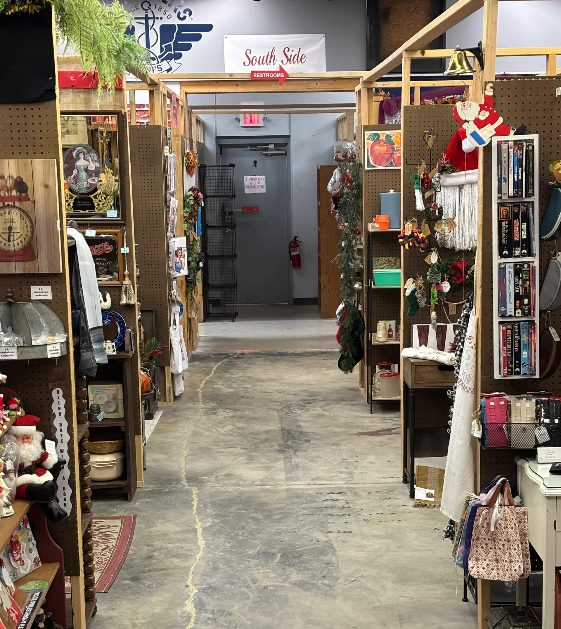 A cozy thrift store aisle filled with various vintage items, decorations, and collectibles on wooden shelves under bright lighting